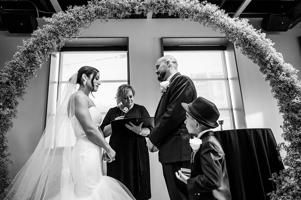 A black and white photograph capturing a tender moment between Nicole and Adam at their wedding.